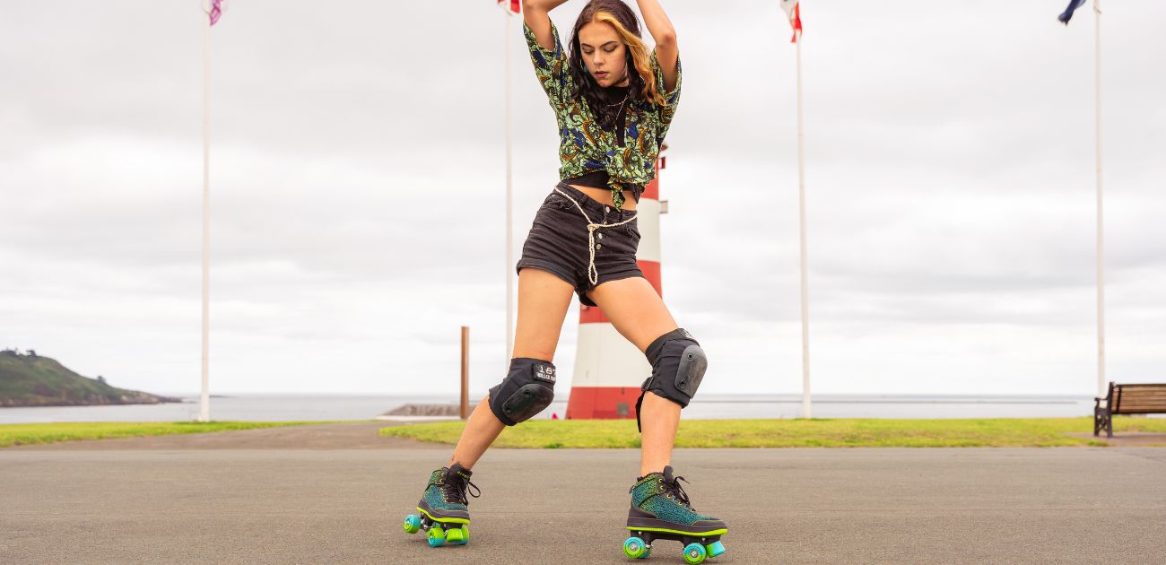 a woman posed in front of some flags at a seafront wearing a pair of Osprey roller skates