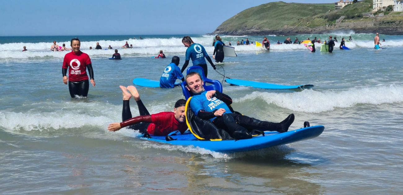 a child learning to swim with The Wave Project on an adapted surfboard