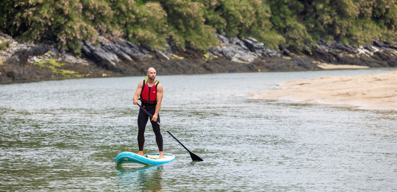 A man paddleboarding down a small area of water