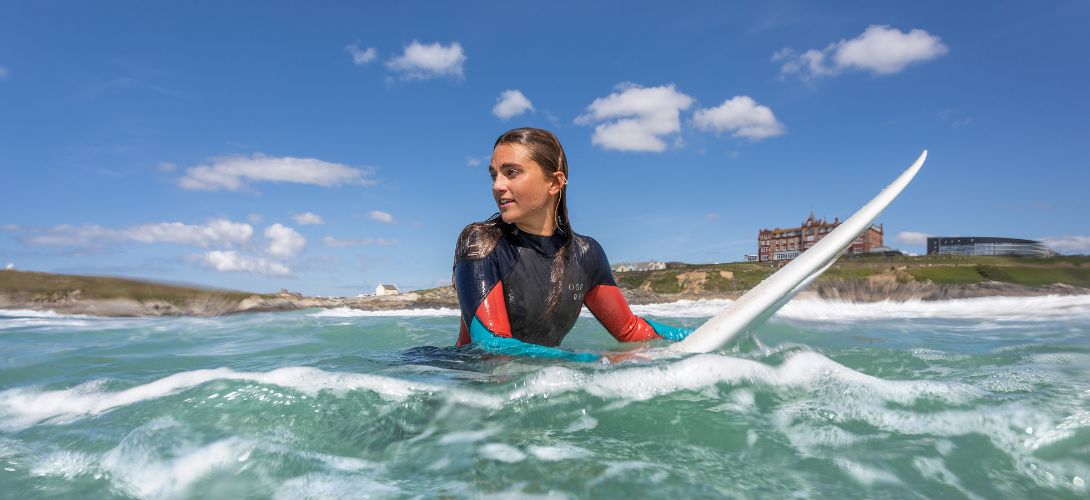 A picture of a female surfer in the water in summer with blue skies behind her